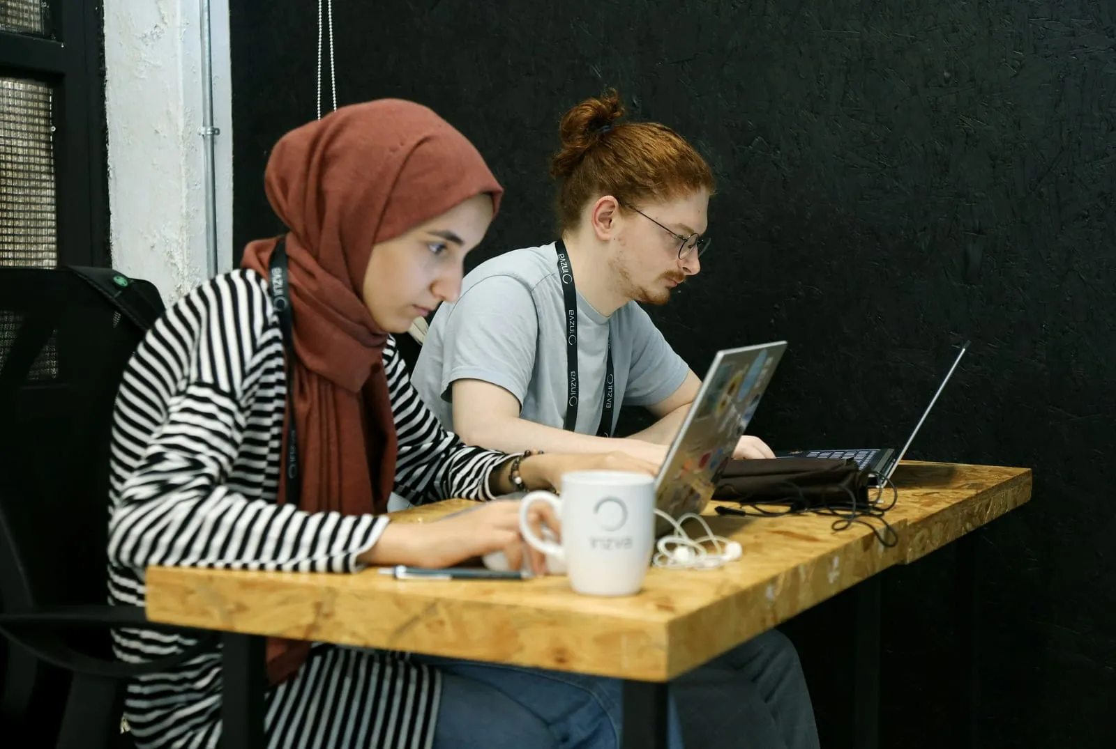 Two developers working side by side on laptops