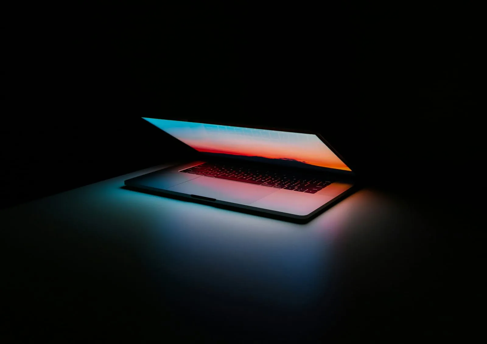 A half-open laptop glowing in a dark room